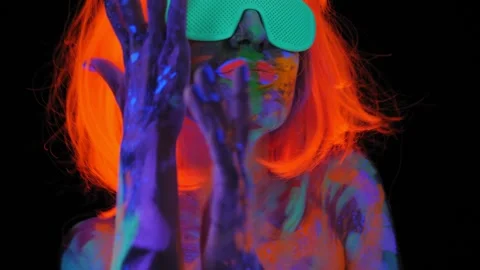 A girl with an UV pattern on her body, wearing an orange wig and green glasses. Stock Footage 266391107