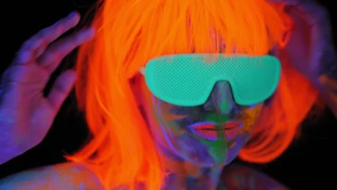 A girl with an UV pattern on her body, wearing an orange wig and green glasses. Stock Footage 266777677