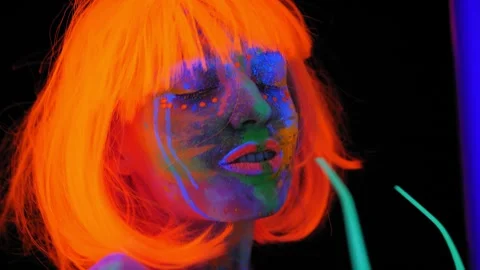 A girl with an UV pattern on her body, wearing an orange wig and green glasses. Stock Footage 267080520