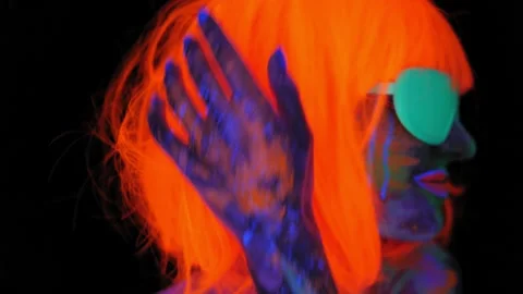 A girl with an UV pattern on her face, wearing an orange wig and green glasses Stock Footage 197465232