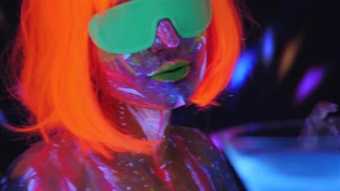 A girl with an UV pattern in an orange wig and glasses with a Martini glass. Stock Footage 221434138