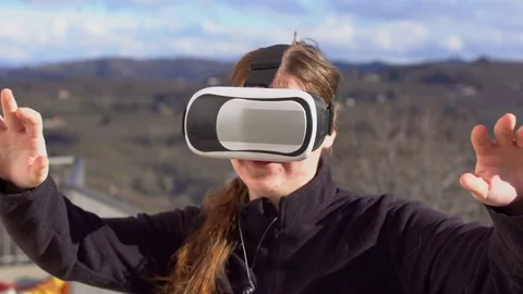 Girl in VR headset looking up at objects in virtual reality beautiful scenery Stock Footage 73660034