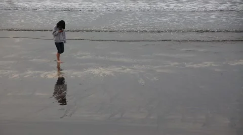 Girl walking and looking at her smart phone on the ocean beach Stock Footage 59158229