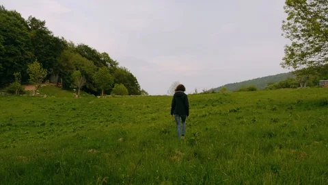 Girl walking away from the camera on open field Stock Footage