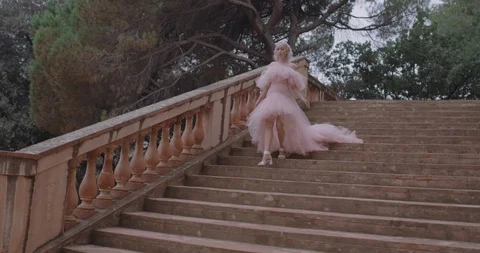 Girl walking down on stairs in pink dress Stock Footage