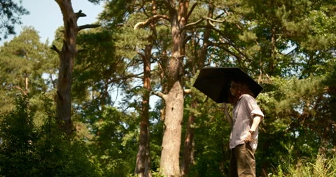 Girl walking forest  using an umbrella as protection from extreme summer heat Stock Footage 340128067