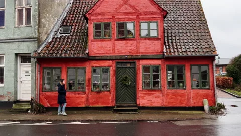 Girl walking in front of rustic red house 库存影片 168119419