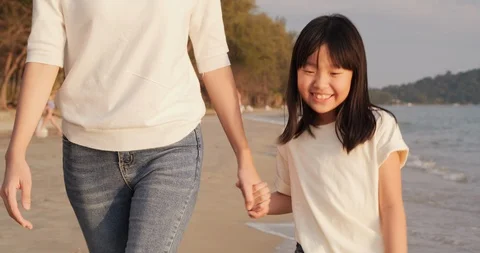 Girl walking with her mother at the beach with attractive smile. Stock Footage