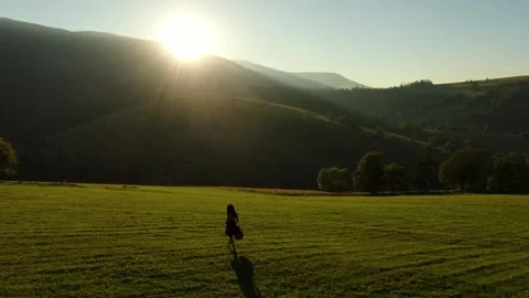 Girl walking on a hill with the guitar against the blue sky and mountains. Stock Footage