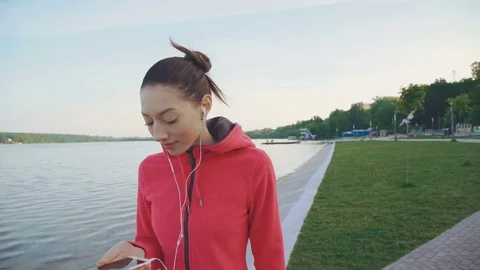 The girl walking near the pool and using earphones 4K Stock Footage