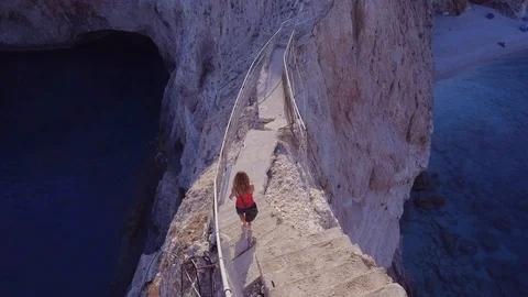Girl walking on ocean cliff Aerial view Stock Footage