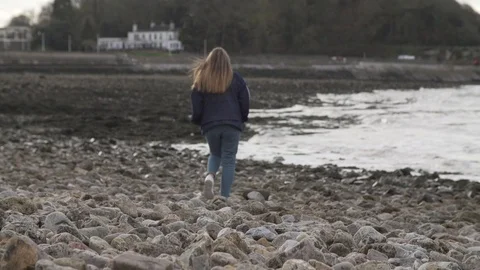 Girl walking on pebbled beach in England Stock Footage