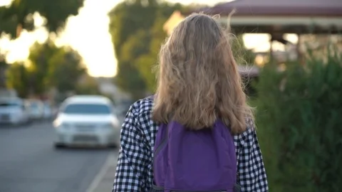 Girl is walking to school on the sidewalk in white sneakers with a purple of Stock Footage 94824853