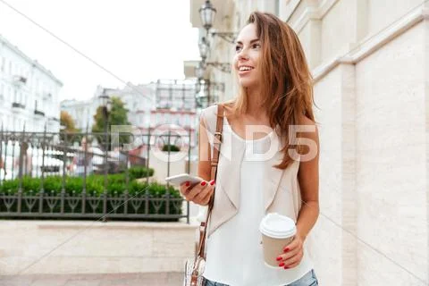 Girl walking on the street and drinking take away coffee Stock Photos