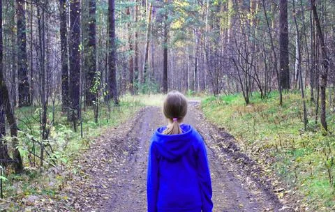 A girl walks alone while walking through the forest on an autumn day. Loneliness Stock Photos