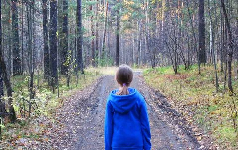 A girl walks alone while walking through the forest on an autumn day. Loneliness Stock Photos