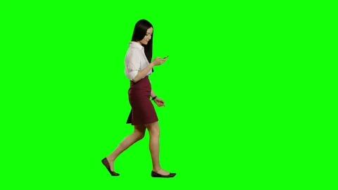 Girl walks and holds a phone and looks at photos. Green screen. Side view Stock Footage