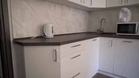 A girl walks into the kitchen and includes a kettle. slender beautiful figure. m Stock Footage 79925473
