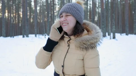 The girl walks in the park in winter and has fun talking on the phone Stock Footage