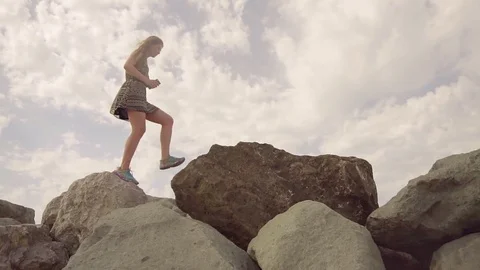 The girl walks on top of the mountain, balancing on a narrow crest, holding a Stock Footage