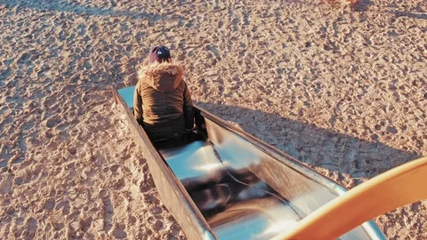 Girl In Warm Jacket Sliding Down Playground Bumpy Metal Slide Video stock 231213038