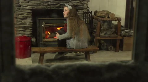 A girl warms her hands in front of a fire -it is snowing outside Stock Footage 44117565