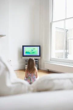 Girl Watching Cartoons In TV At Home Stock Photos