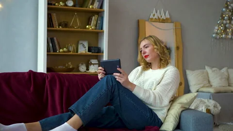 Girl is watching video using a tablet at home in spacious hotel Stock Footage 194741938