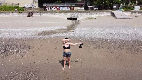 Girl waving her hands while standing at the surf line on the beach at sea. Stock-Footage 247185959