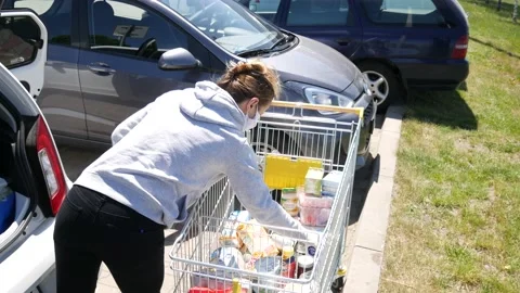 Girl wearing face mask, loading car with groceries during Coronavirus, COVID-19. Stock Footage 145831993