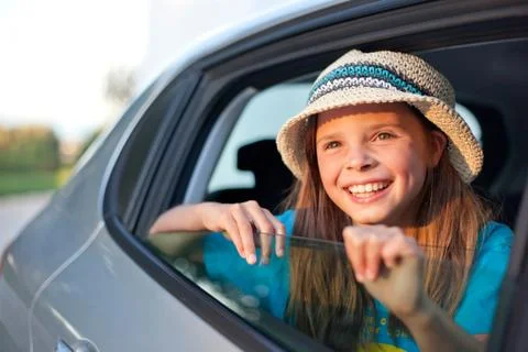 Girl wearing hat looking through open car window, smiling Stock Photos