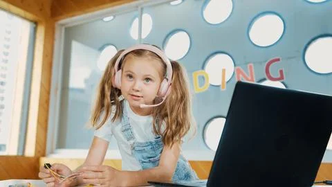 Girl wearing headphone while study equipment and looking at camera. Erudition. Stockfoto's