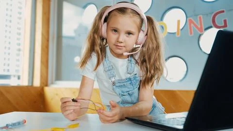 Girl wearing headphone while study equipment and looking at camera. Erudition. Stockfoto's