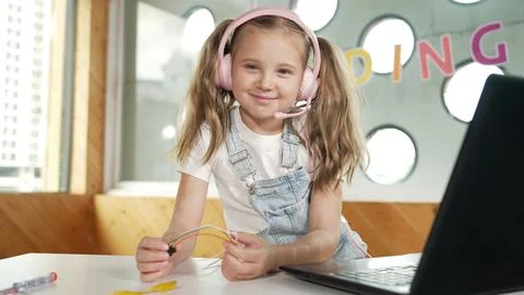 Girl wearing headphone while study equipment and looking at camera. Erudition. Stockfoto's