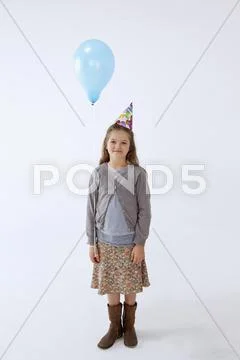 A girl wearing a party hat and holding a balloon Stock Photos