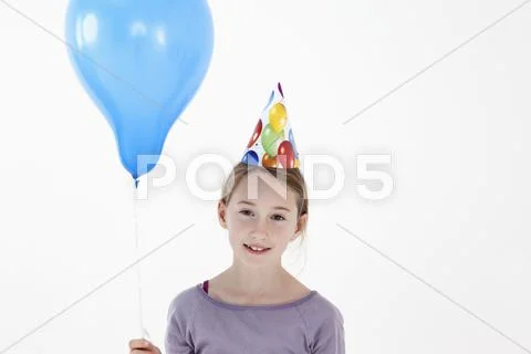 A girl wearing a party hat and holding a balloon, close-up Stock Photos
