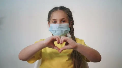 Girl wearing safety mask. Child hands heart thanks to doctors. Coronavirus Stock Footage
