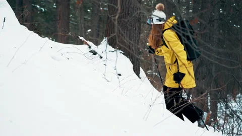 Girl with a white hat in the forest with a backpack and hiking sticks climbing a Stock Footage 144692391