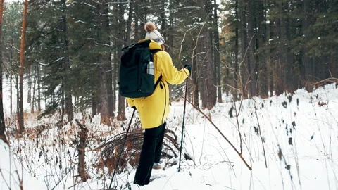 Girl with a white hat in the forest with a backpack and hiking sticks in winter Video stock 144692808
