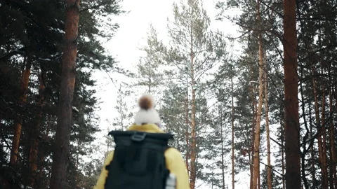 Girl with a white hat in the forest with a backpack and hiking sticks in winter Video stock 144693115