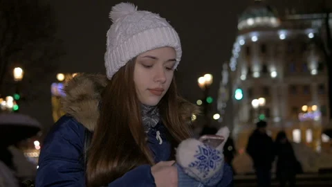 A girl in a white hat, in winter, walks down the street and reads a message on Video stock 85719829