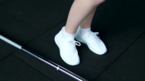 Girl in white sneakers develops ankle Woman stretches ankle on treadmill closeup Video stock 305995137