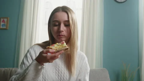 Girl in a white sweater eats a slice of Italian pizza Stock Footage 138221288