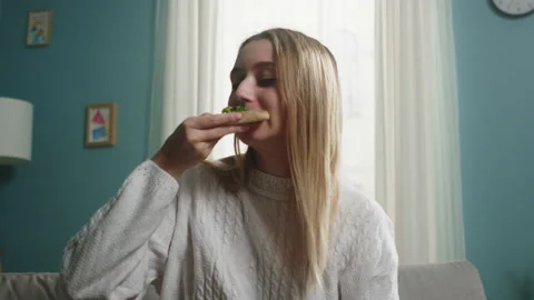 Girl in a white sweater eats a slice of Italian pizza Stock Footage 138222525