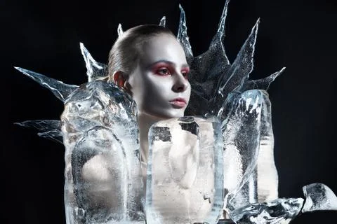 Girl with whitened skin and red make-up in ice on a black background Stock Photos