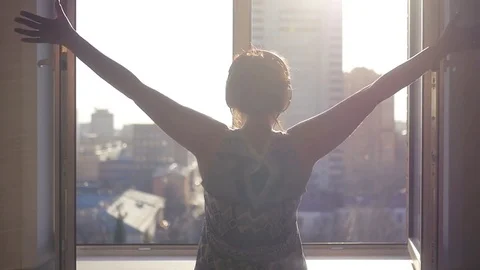 The girl at the window, hands up in the glad spring sun. Listening to music on Stock Footage 75030277
