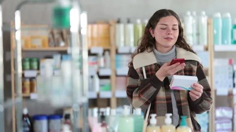 Girl in winter clothes scans code on package of pills to check the expiration Stock Footage 308957086