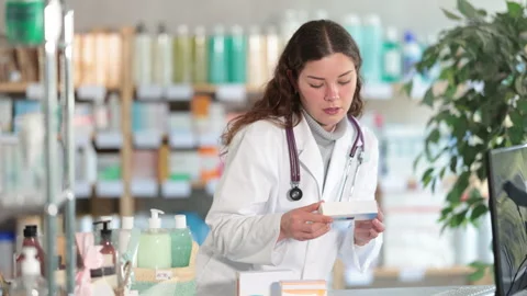 Girl in winter clothes scans code on cough syrup to check the expiration date Stock Footage 311839975