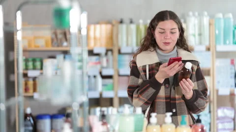 Girl in winter clothes scans code on cough syrup to check the expiration date Stock Footage 329395872