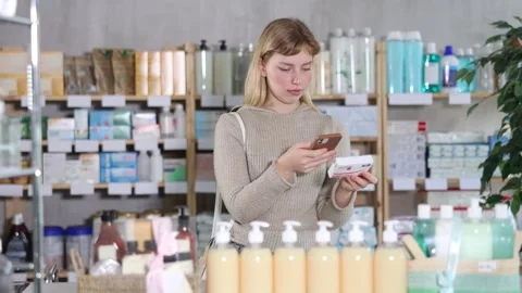 Girl in winter clothes scans code on package of paracetamol pills to check the Stock Footage 329540820